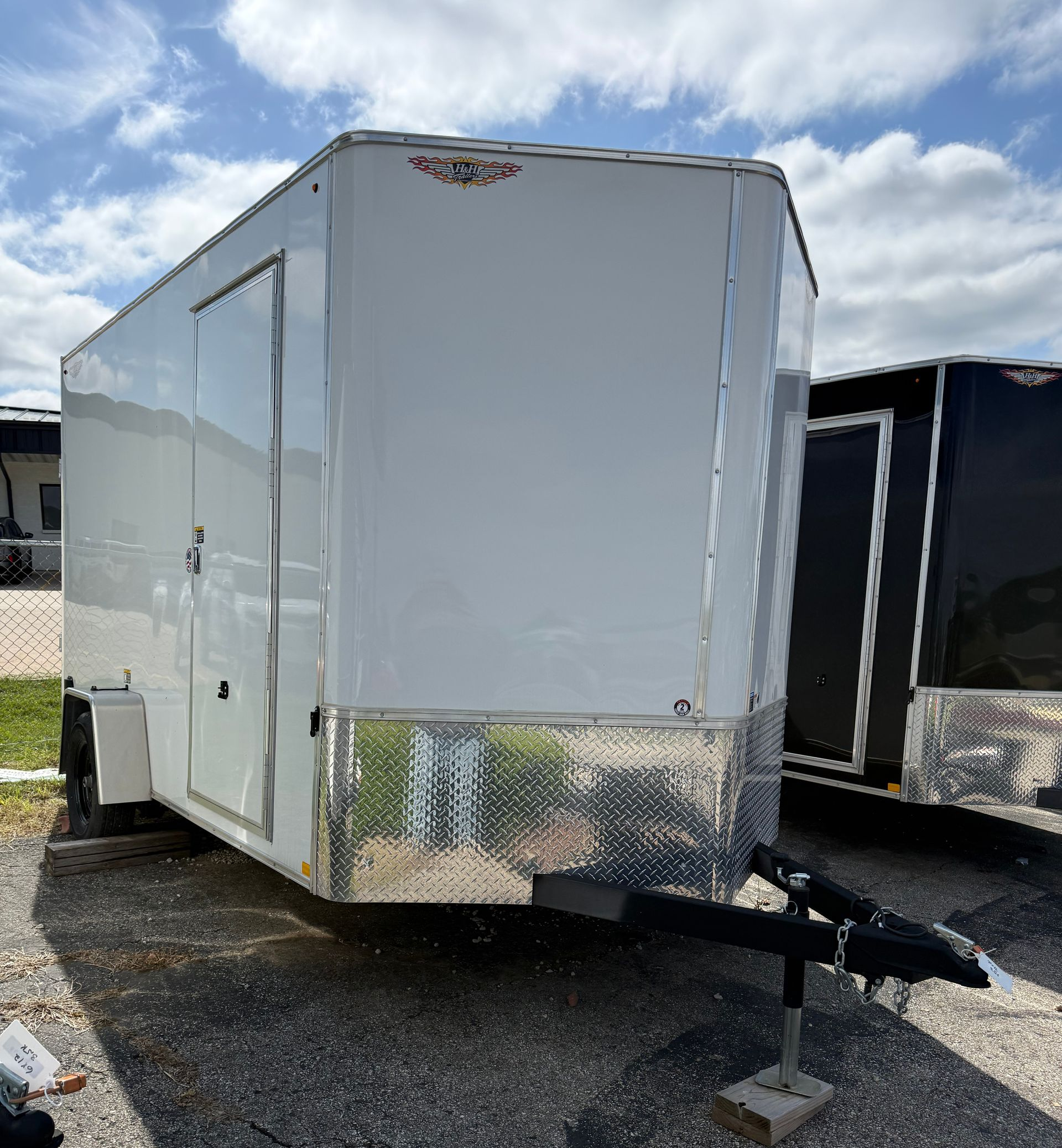 Black flatbed trailer with two axles parked on cracked pavement