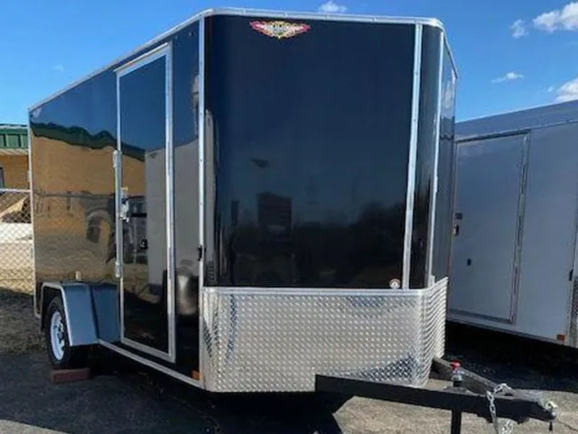 Black enclosed cargo trailer with diamond plate front and white wheels