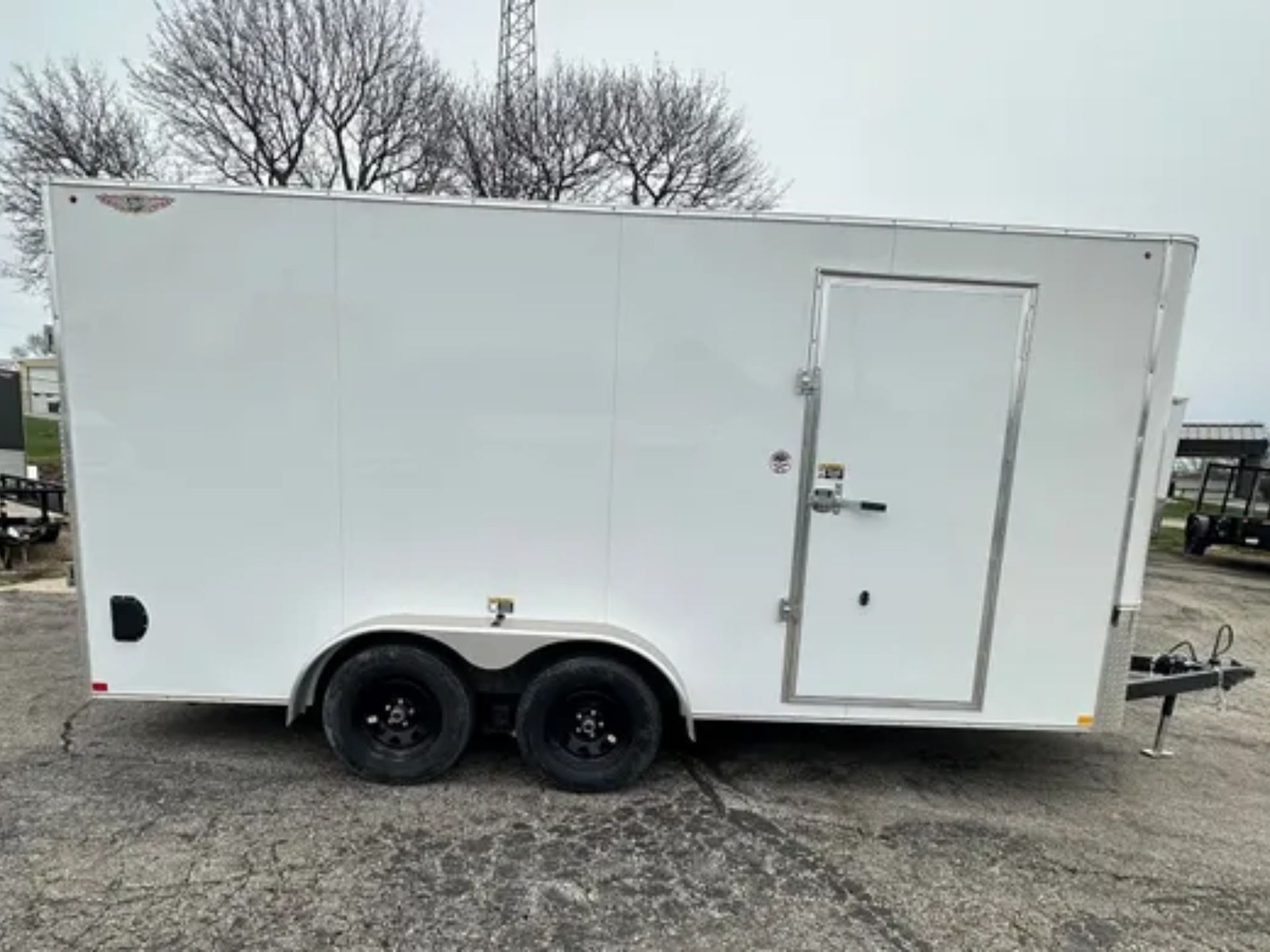 White enclosed cargo trailer with black wheels, door, and metal trim