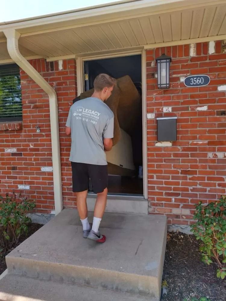 A man is carrying a large box into a brick house.