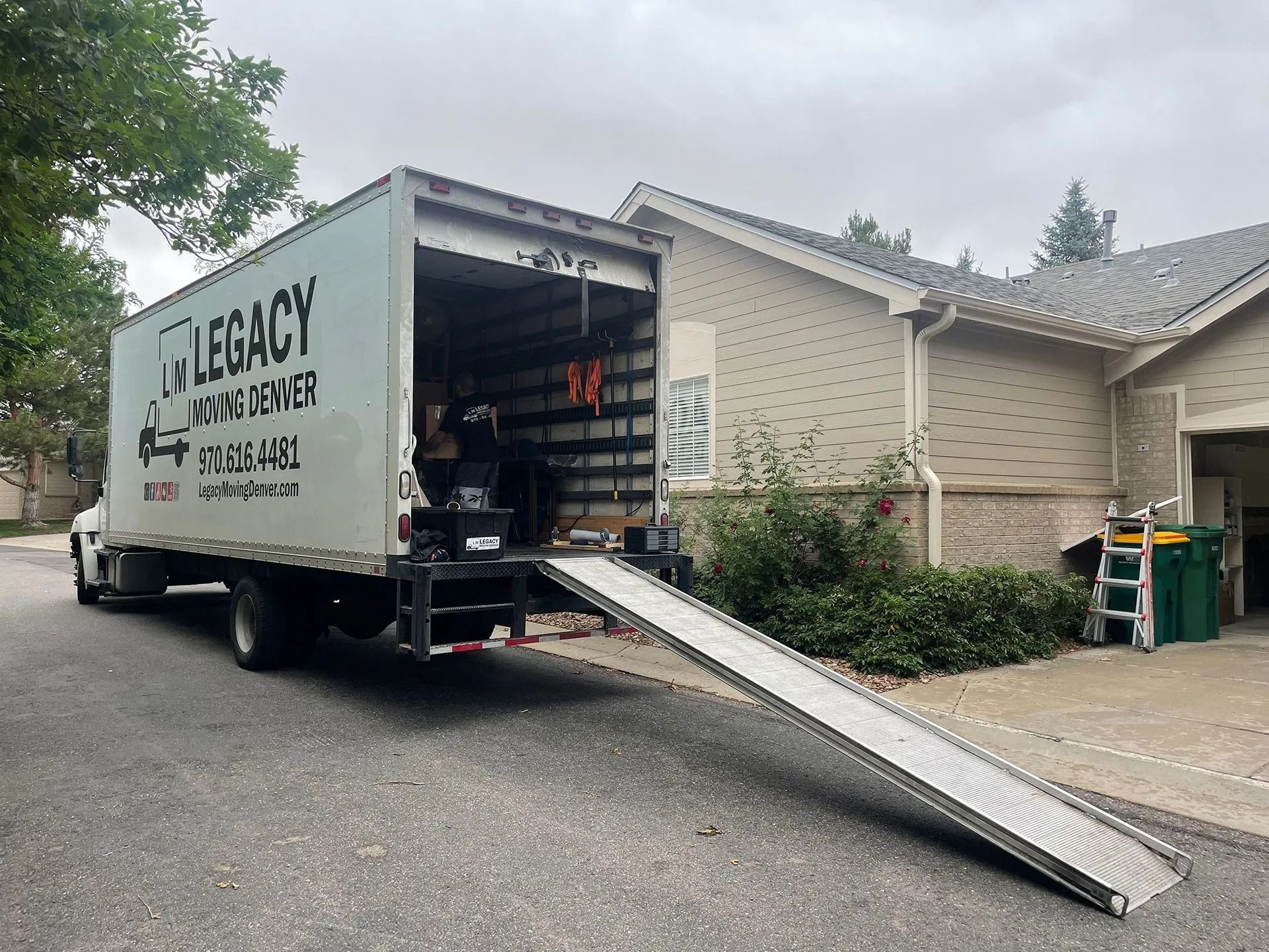 A legacy moving truck is parked in front of a house.