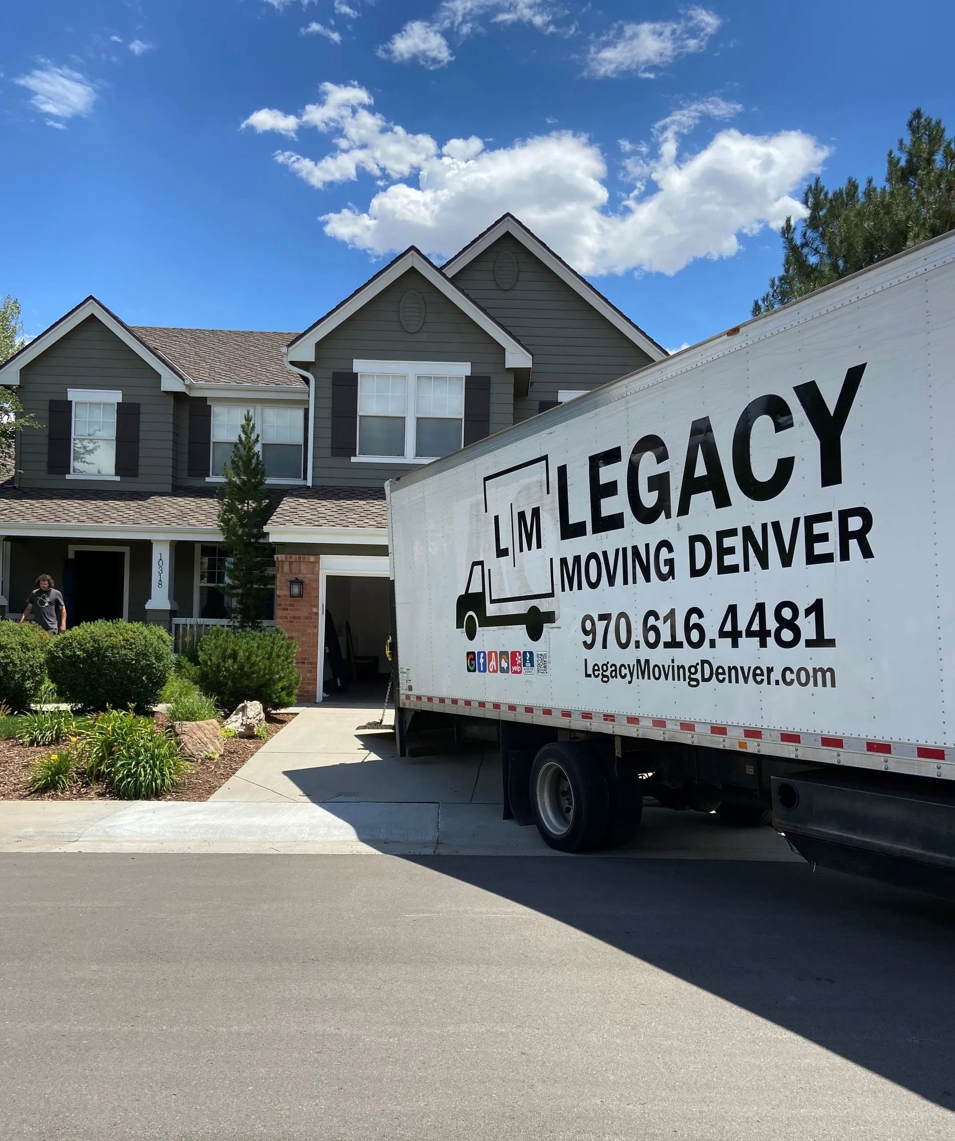 Three people are sitting on the back of a moving truck.