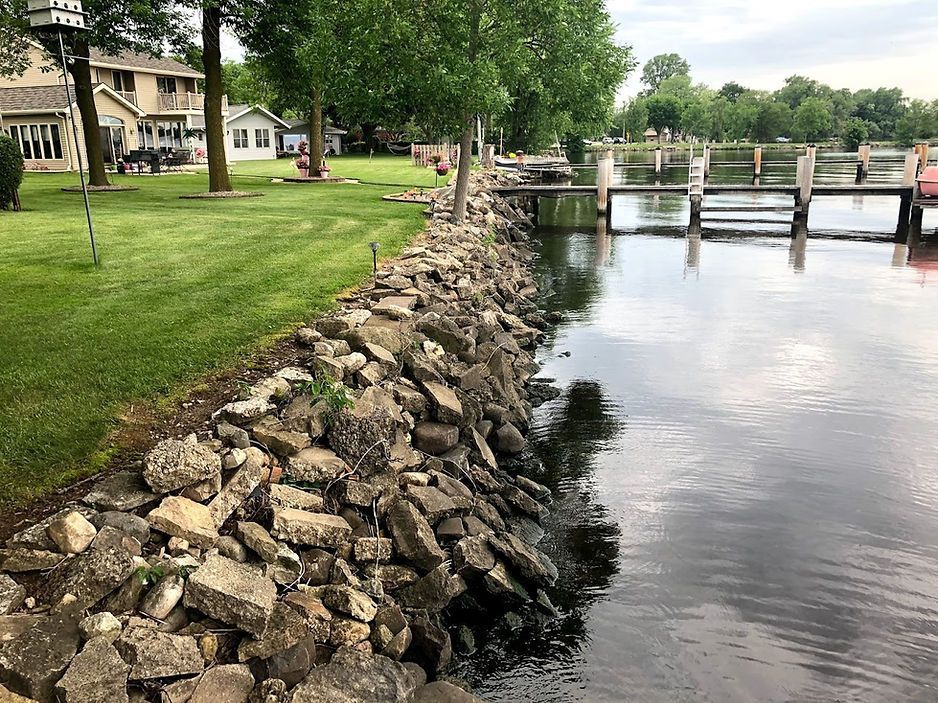 A river with a dock and a lot of rocks on the shore - before