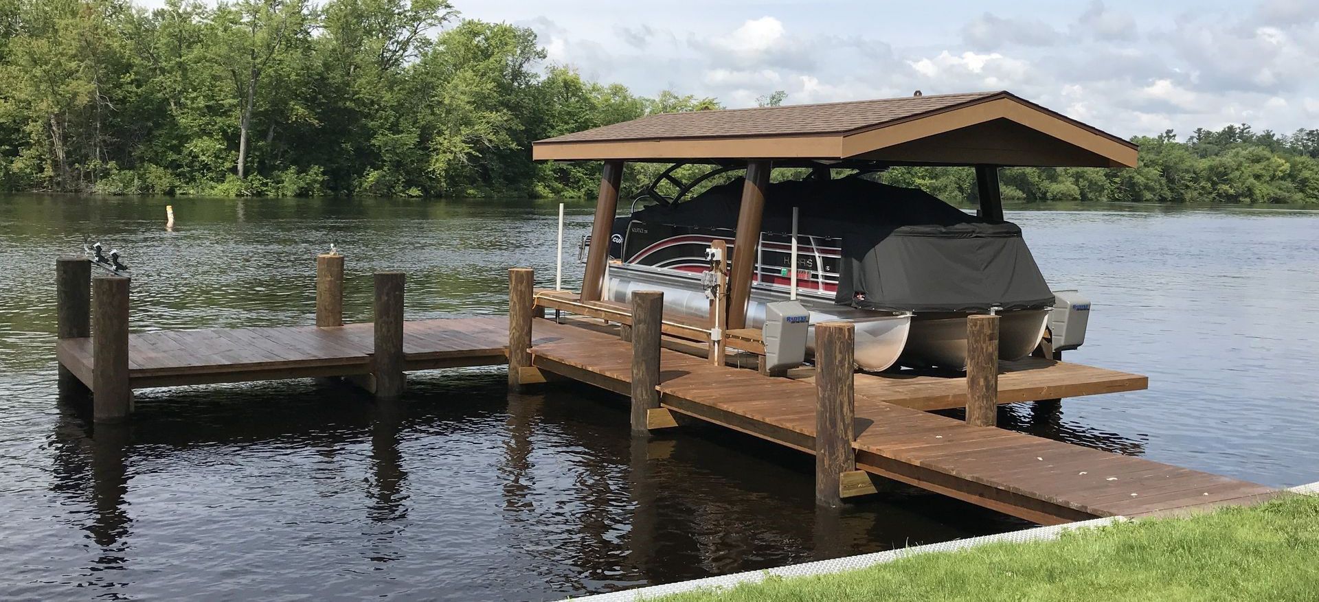 A boat is situated on a boat lift at a lakeside dock