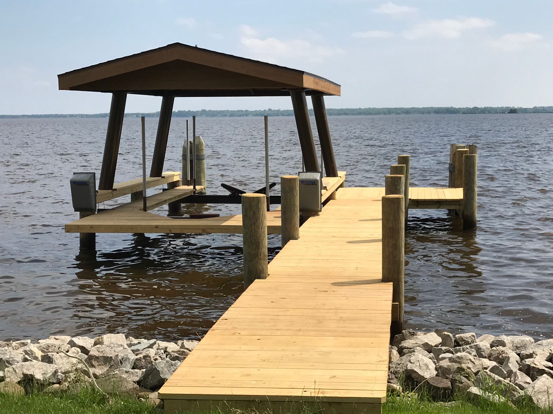 A wooden dock with a boat lift on it is in the middle of a lake.