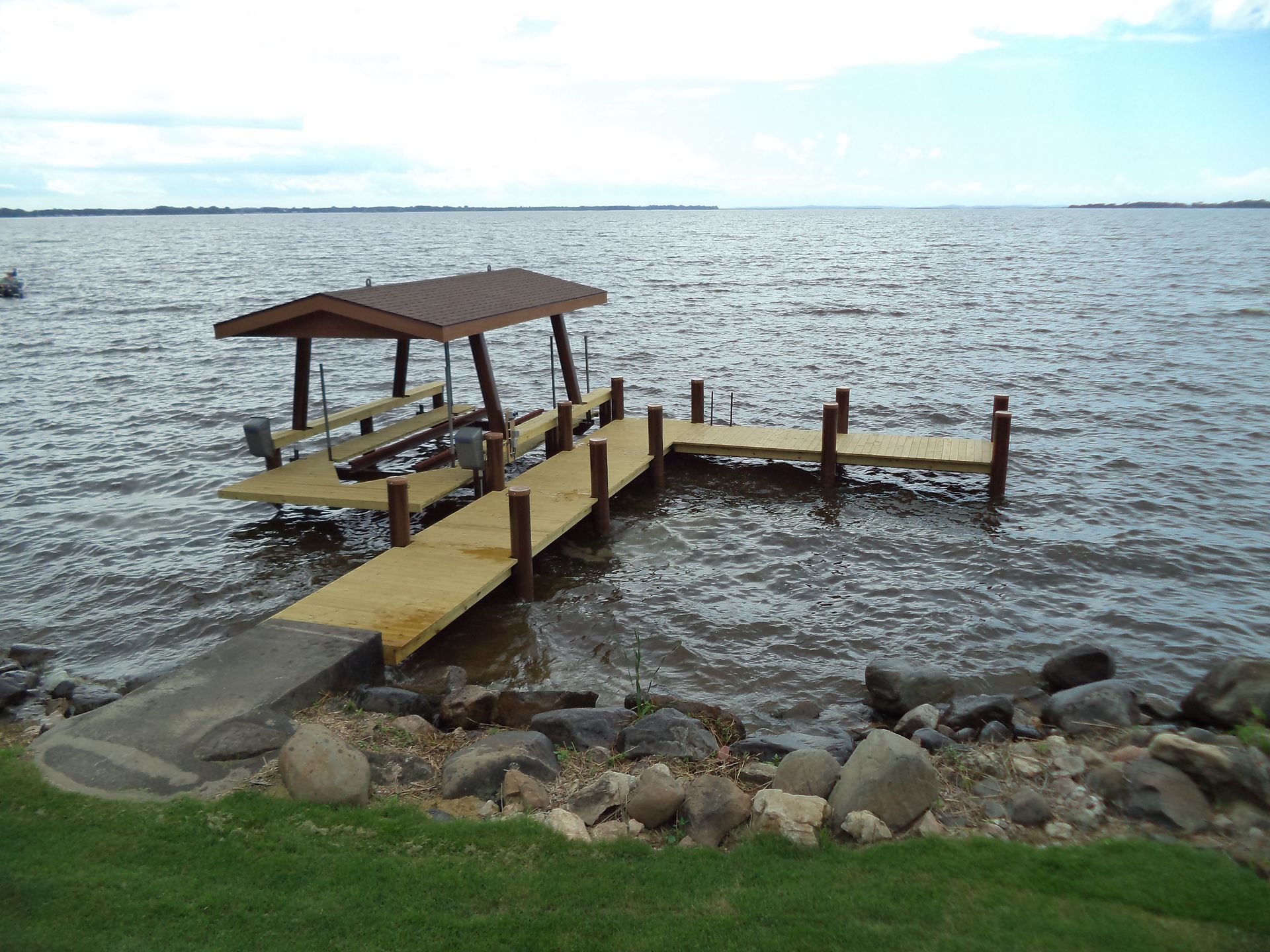 A wooden dock with a roof is in the middle of a large body of water.