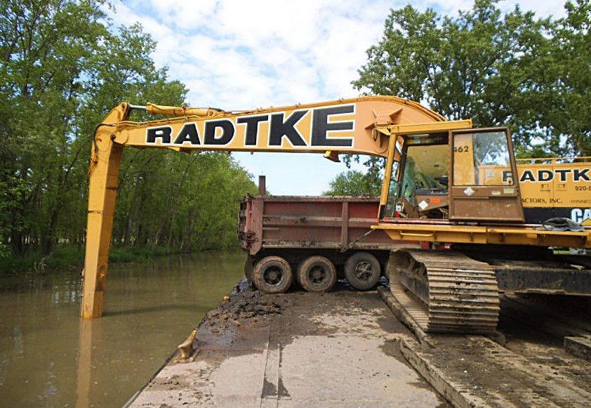 A large yellow radtke excavator is in a flooded area