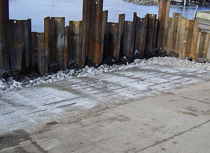 A row of wooden poles are lined up on the side of a road