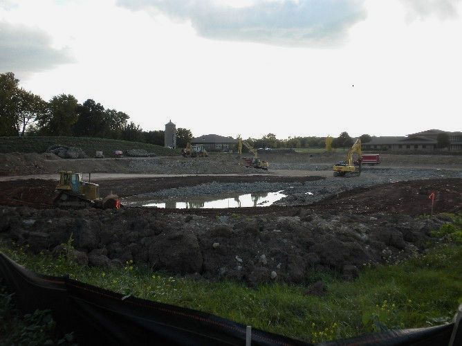 A construction site with a lot of dirt and a fence in the foreground