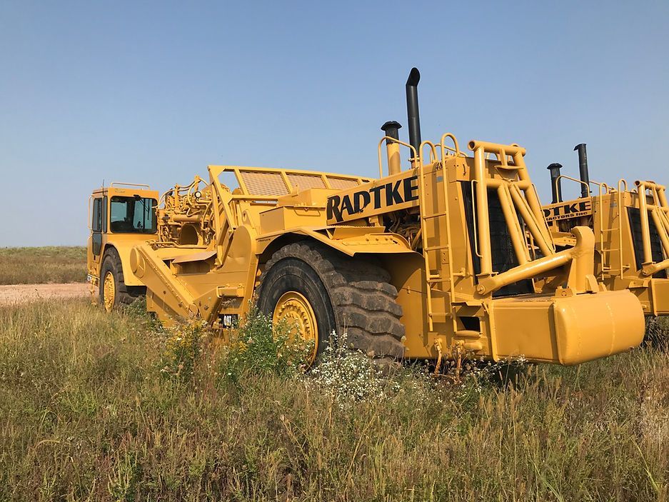 Two yellow tractors are parked in a grassy field.