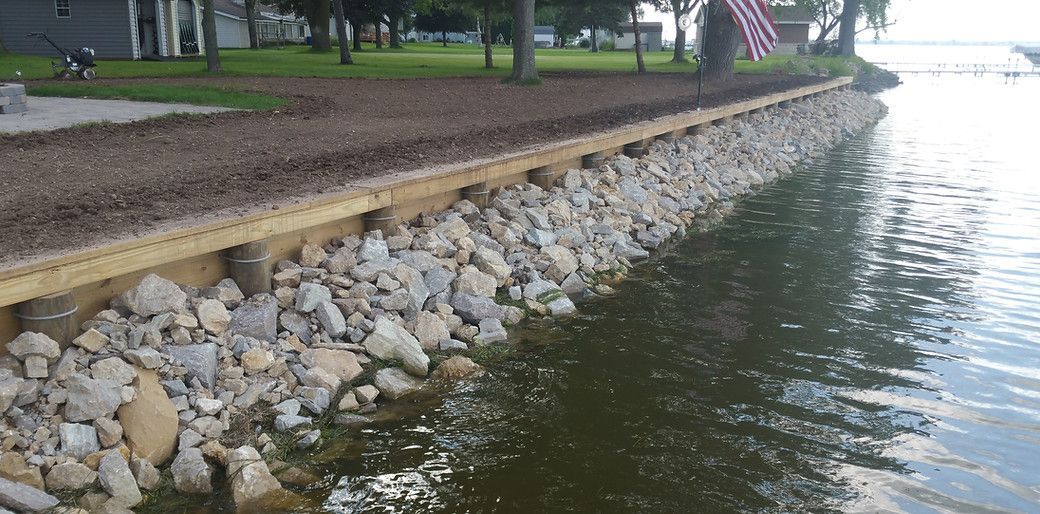 A large body of water surrounded by rocks and a wooden shoreline.