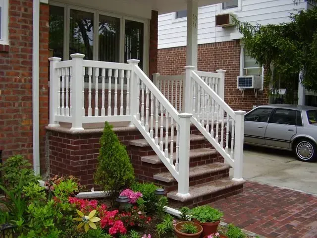A white porch with stairs and a car parked in front of it