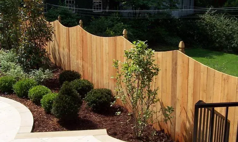 A wooden fence surrounds a lush green yard