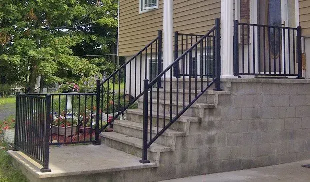A house with a porch and stairs with a black railing.