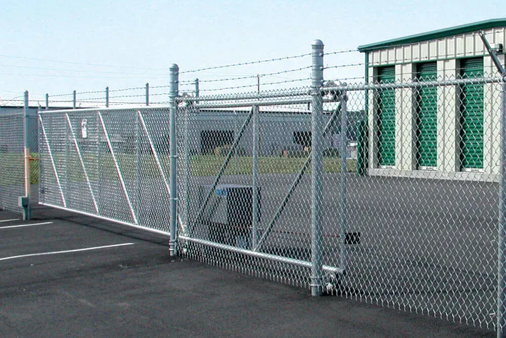 A chain link fence with a sliding gate in front of a storage building