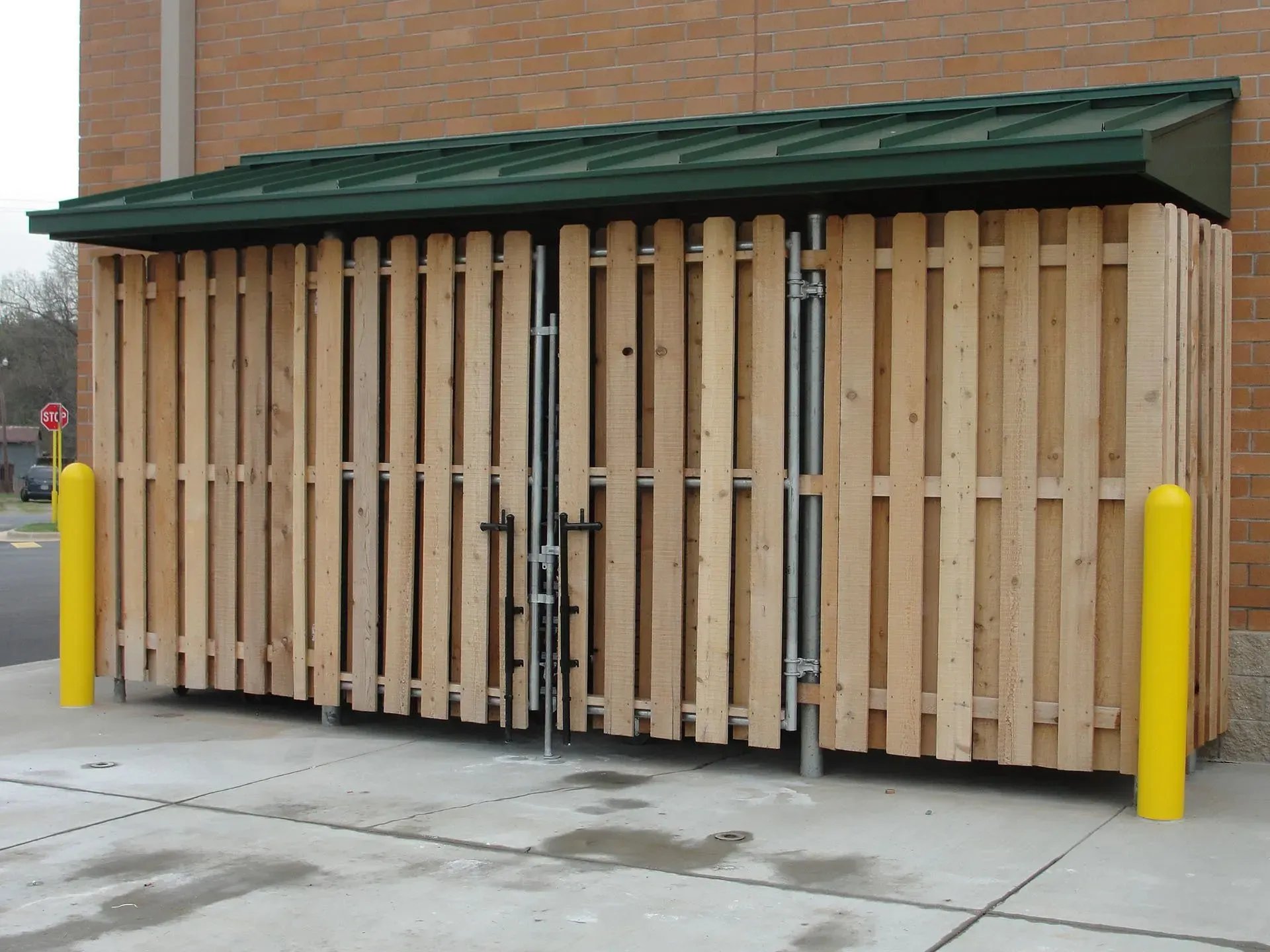 A wooden fence with a green roof and yellow poles
