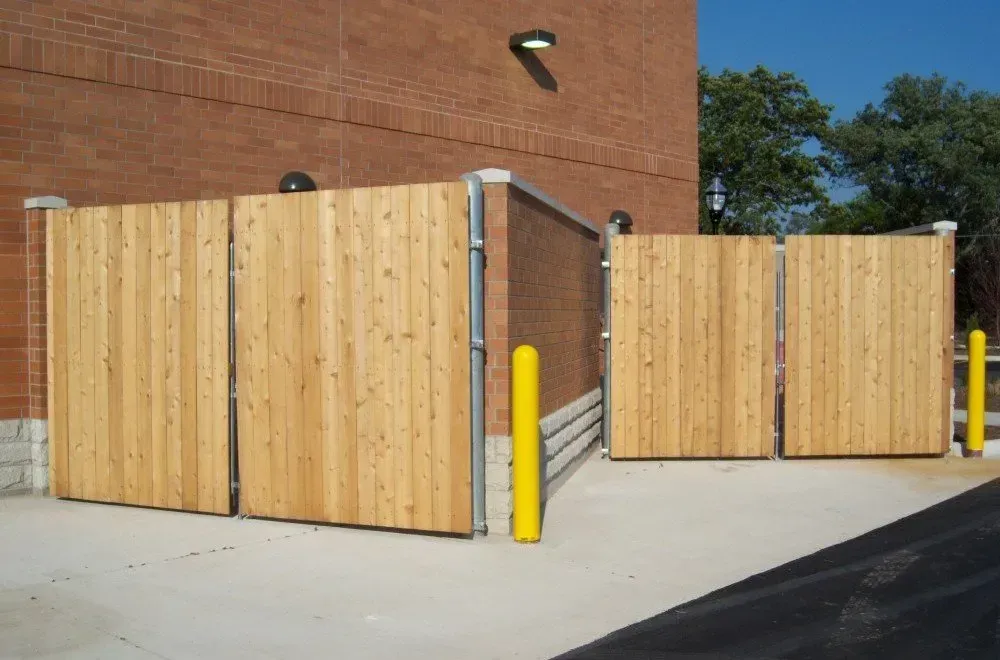 A wooden fence with yellow poles in front of a brick building