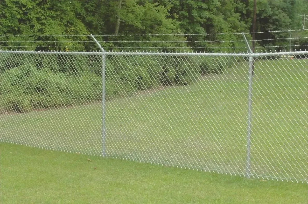 A chain link fence is surrounding a grassy field.