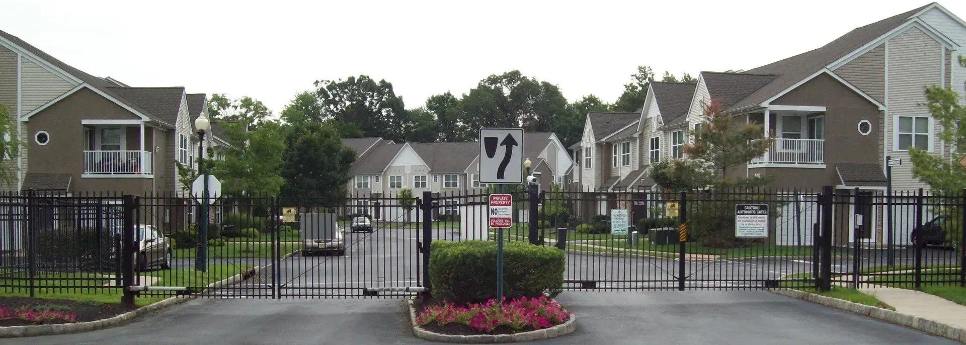 A gated entrance to a residential area with a no parking sign