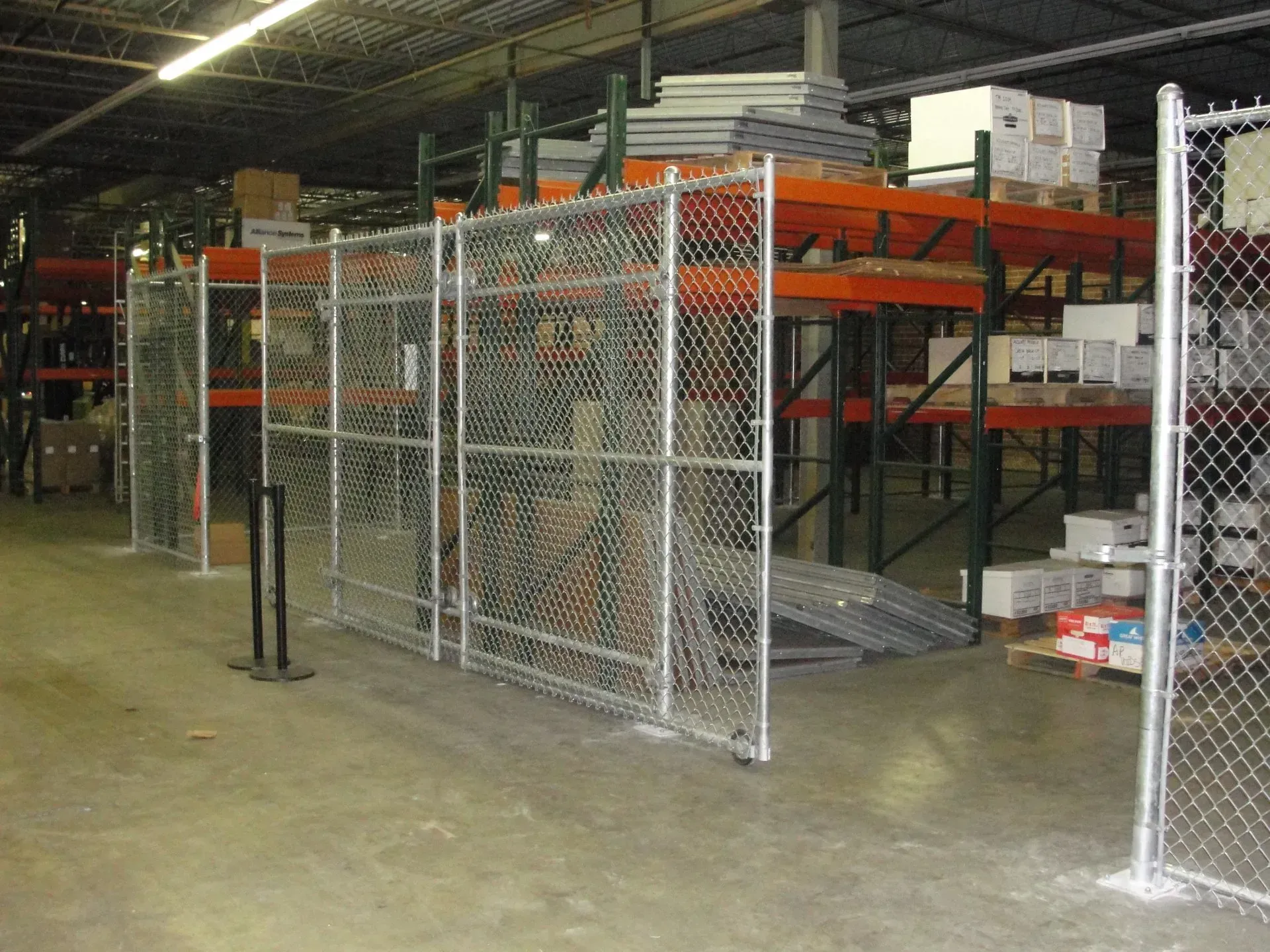 A chain link fence surrounds a large warehouse