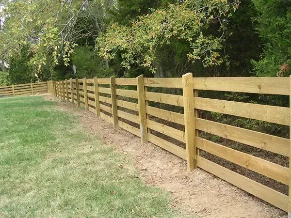 A wooden fence surrounds a lush green field
