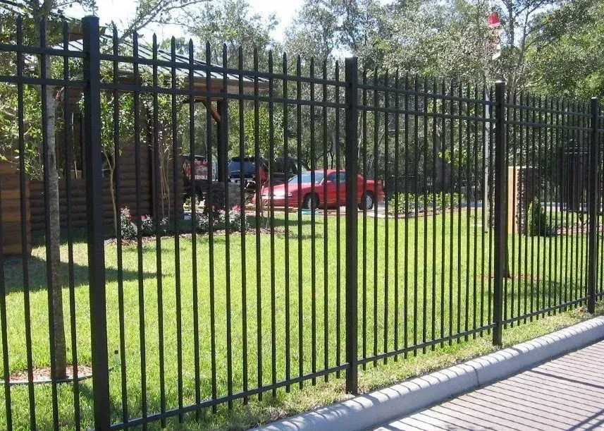A black metal fence surrounds a lush green yard