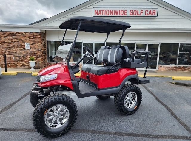 Red golf cart with black roof and large off-road tires, parked in front of a