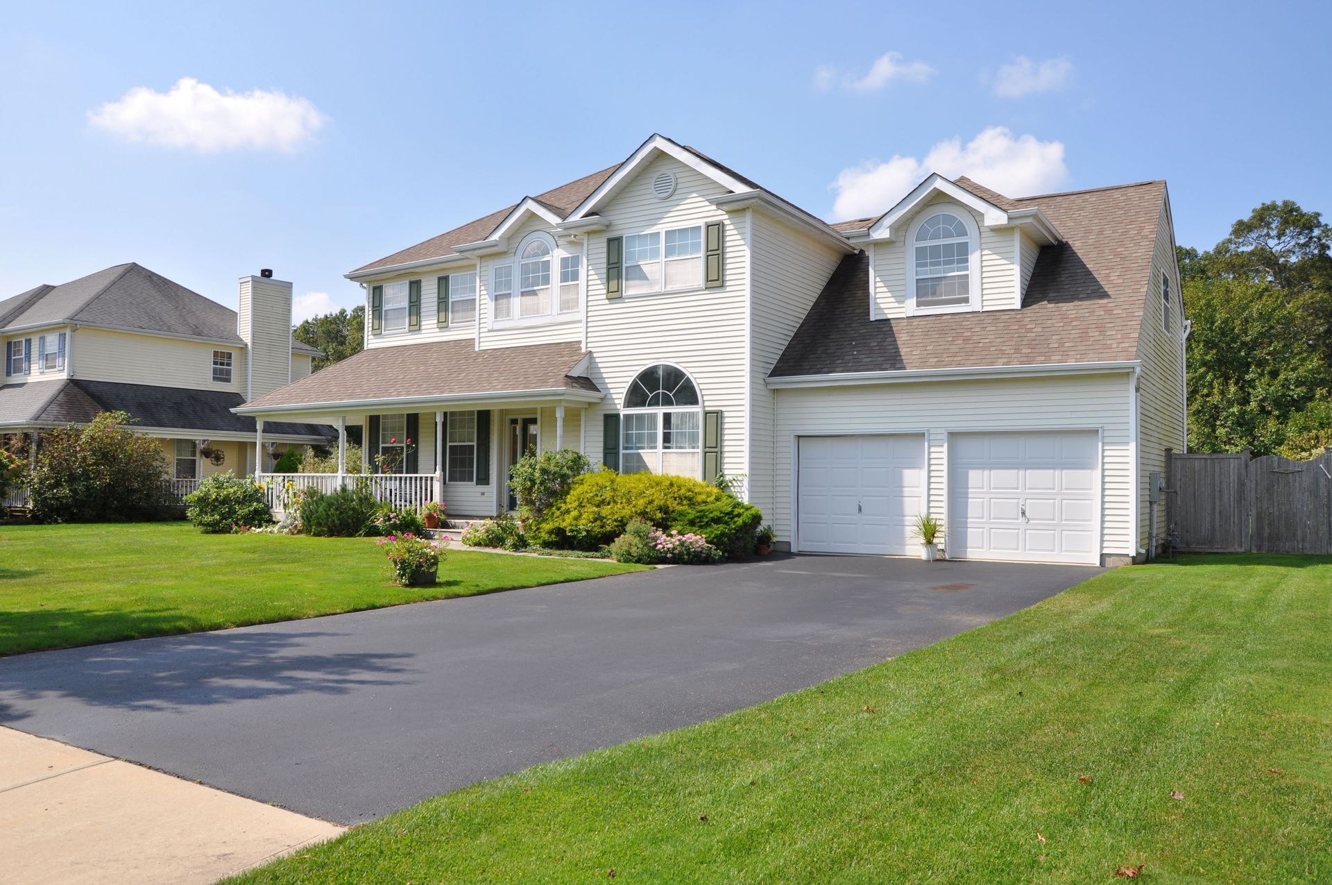 Two-story house with white siding, two-car garage, and a long black driveway.