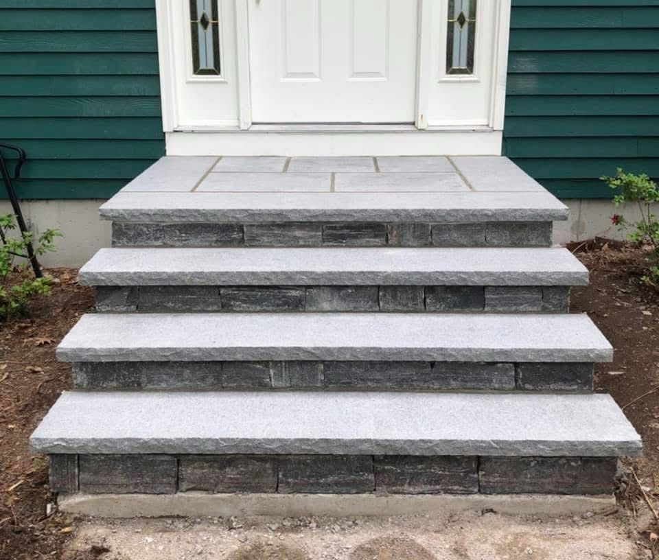 Front steps with five gray stone risers leading to a white front door