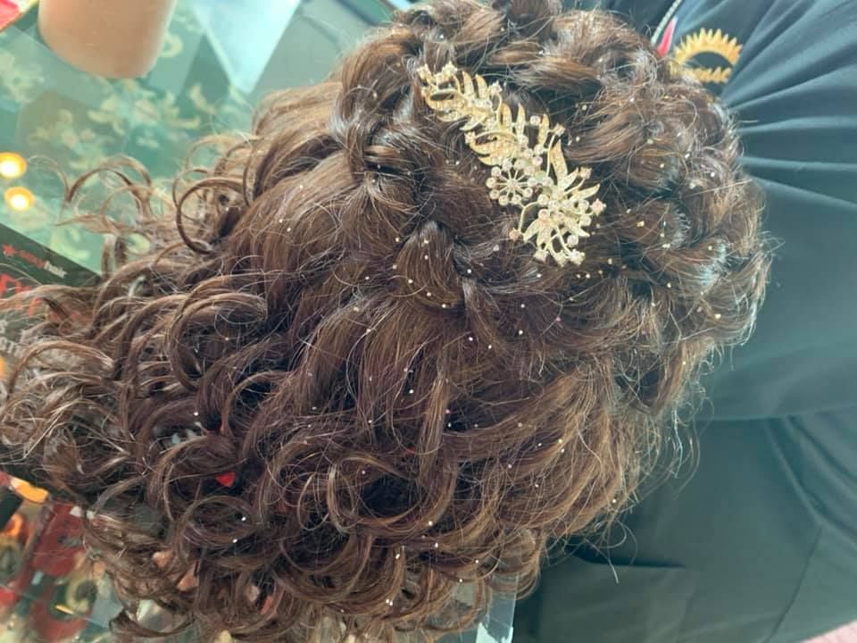 a woman with curly hair is wearing a comb in her hair .