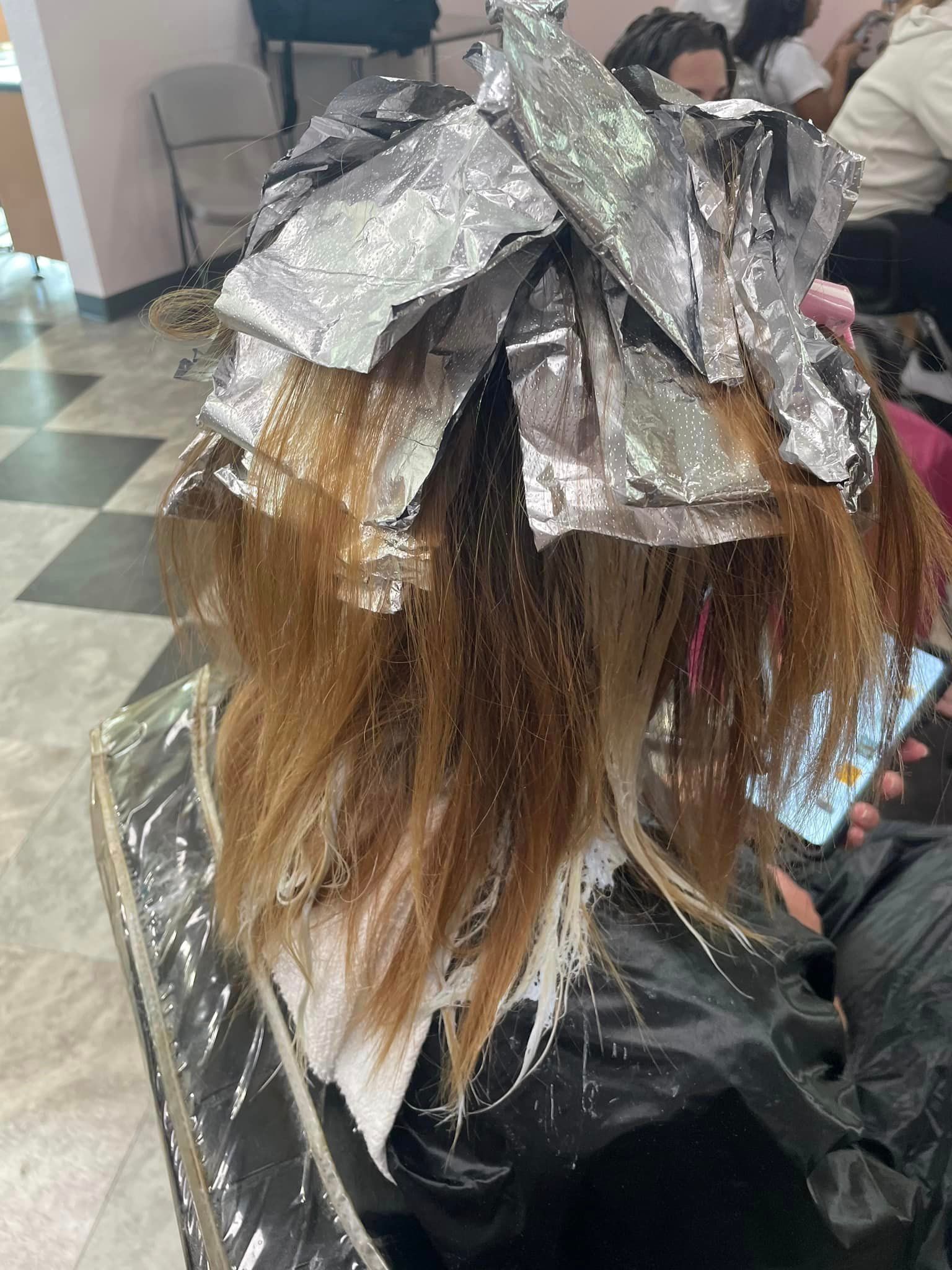 a woman is getting her hair dyed in a salon .