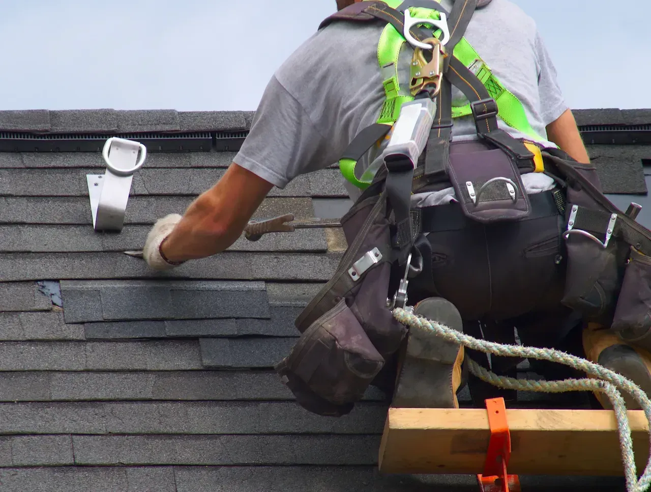 A man wearing a harness is working on a roof