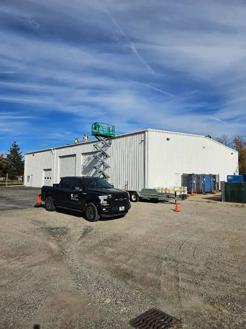 A black truck is parked in front of a large white building.
