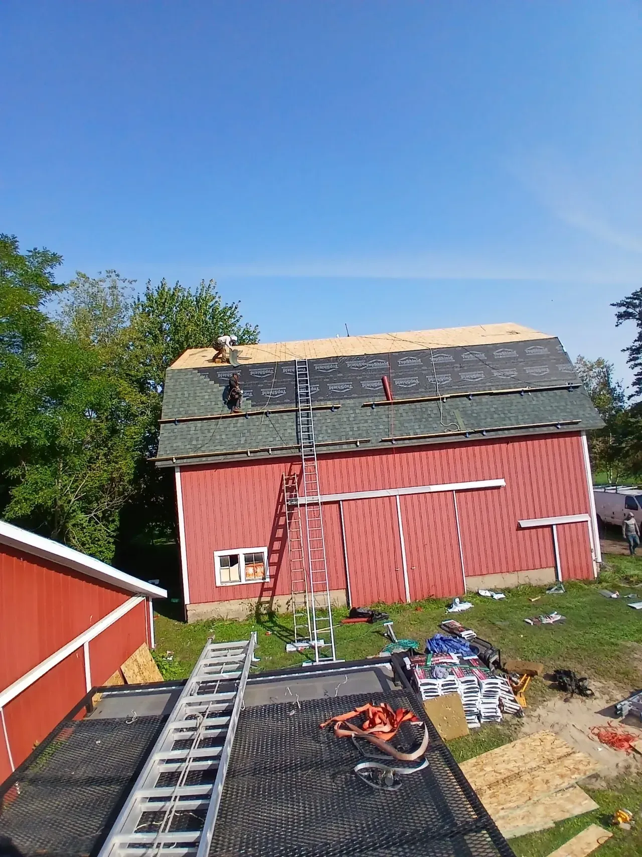 A red barn is being remodeled with a green roof.