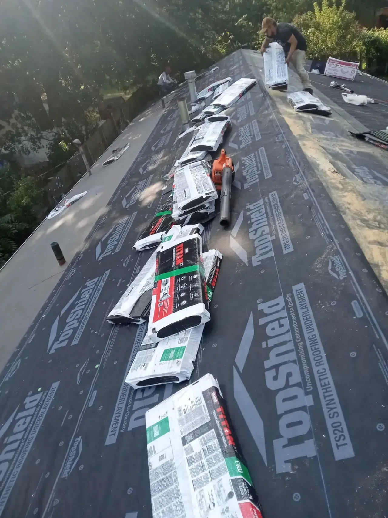 A man is working on a roof with topshield shingles.