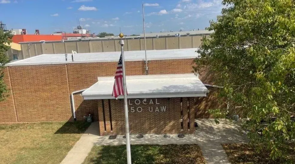 An american flag is flying in front of a brick building.