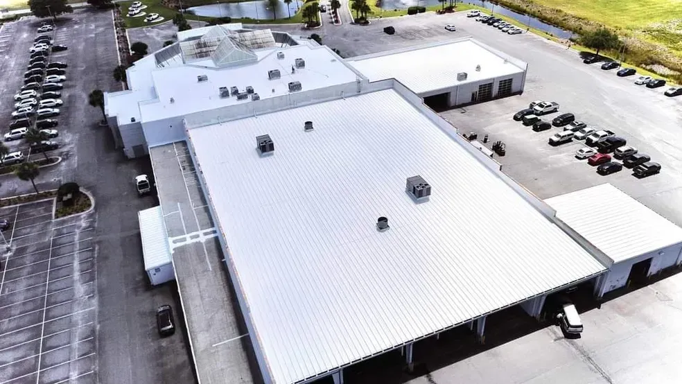 An aerial view of a large white building with a parking lot in front of it.