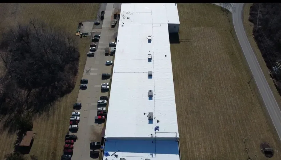 An aerial view of a large building with a white roof.