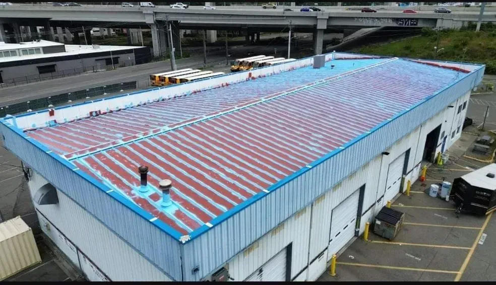 An aerial view of a large building with a roof that is being painted.