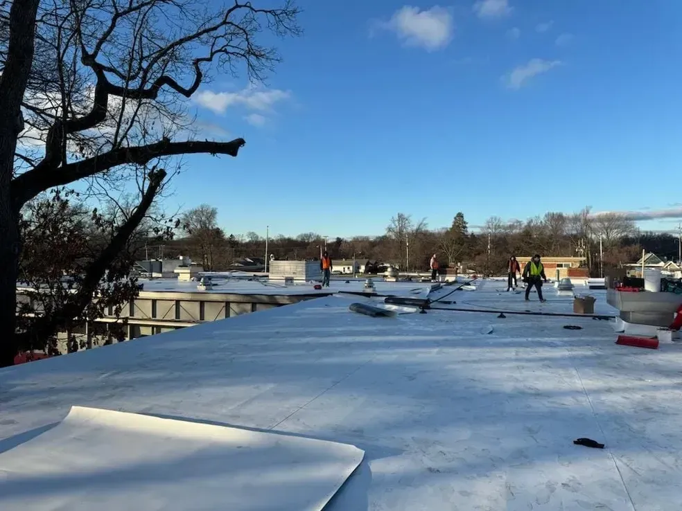A group of people are standing on top of a snow covered roof.