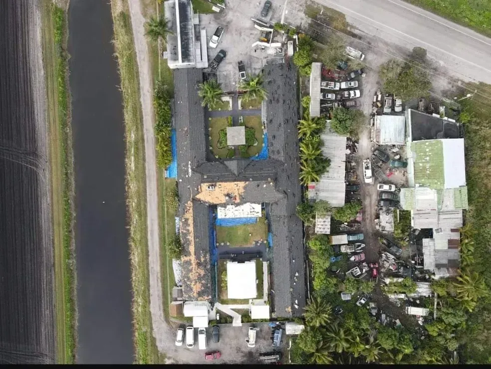 An aerial view of a large building surrounded by trees and a river.