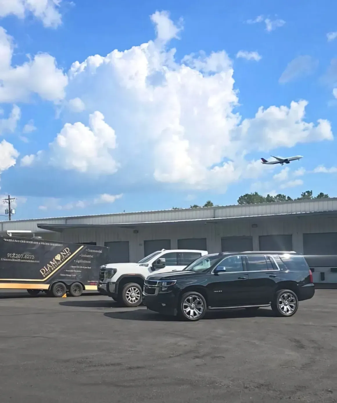 A black suv is parked in front of a building with a plane flying in the background