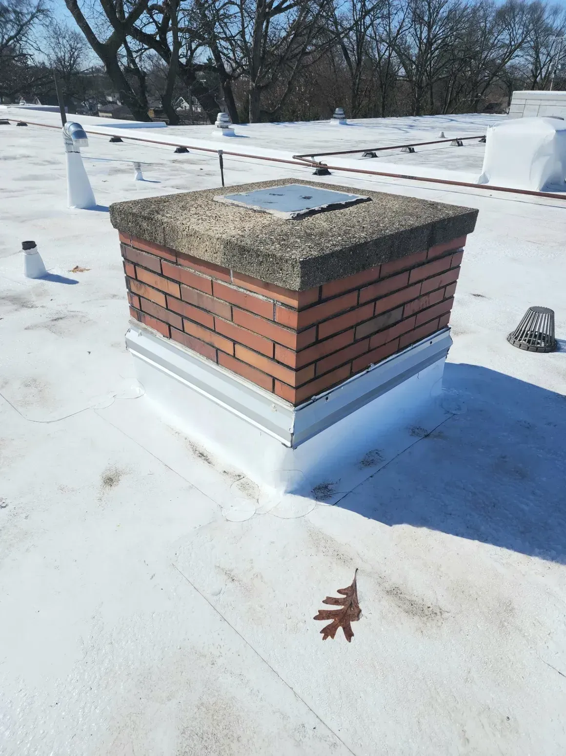 A brick chimney is sitting on top of a white roof.