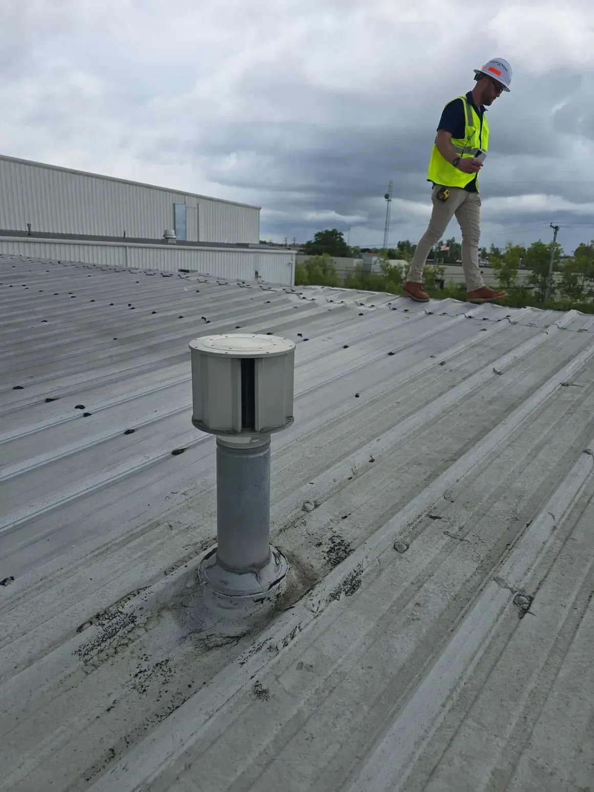 A man in a yellow vest is standing on the roof of a building