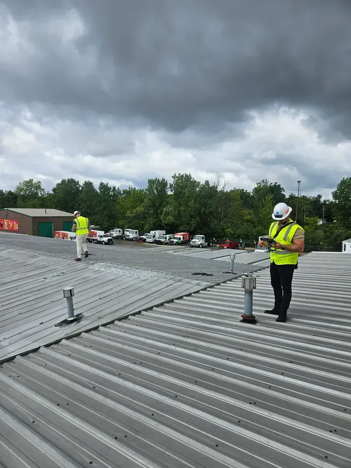 Two men are standing on top of a metal roof.
