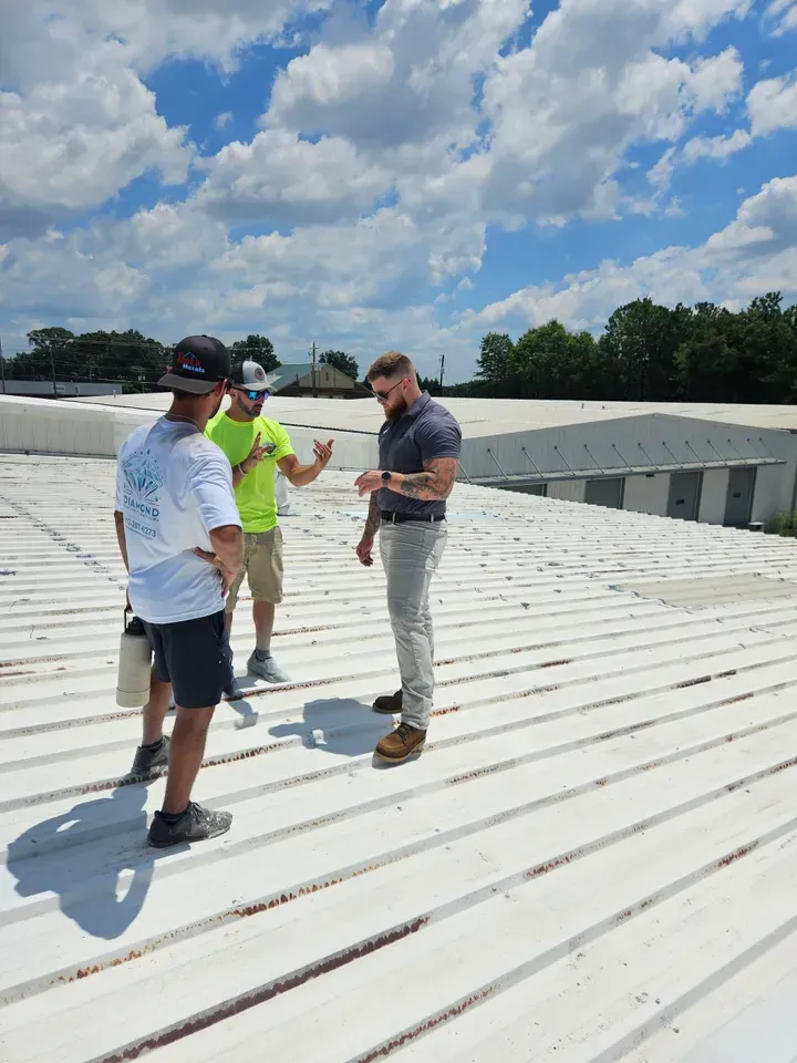 Three men are standing on top of a white roof.