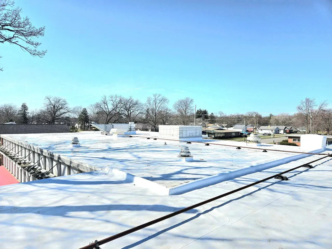 The roof of a building is covered in snow on a sunny day.