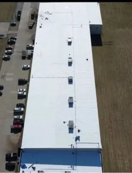 An aerial view of a large building with a white roof