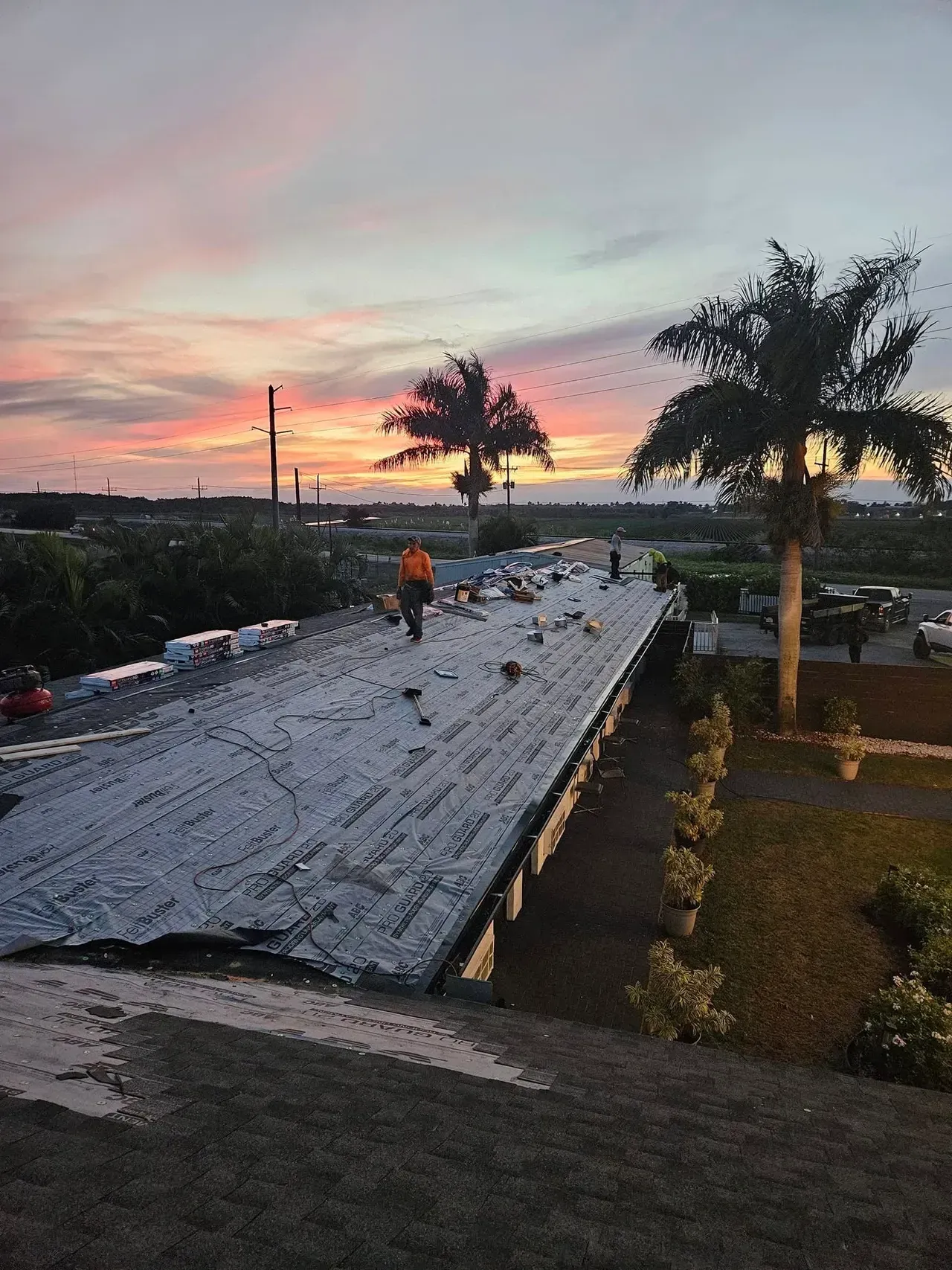 A man is working on the roof of a building at sunset.