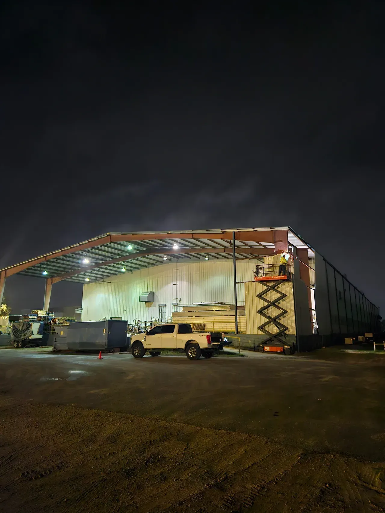 A man is standing on a ladder on top of a building at night.